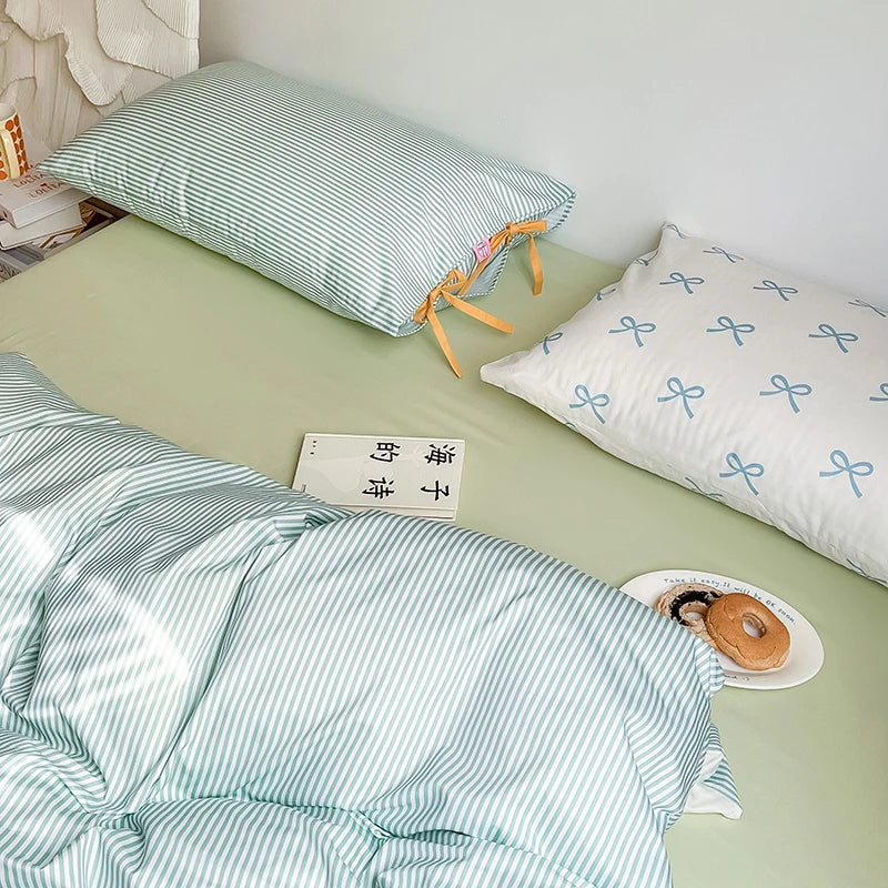 Blossom Bow Bedding Set styled on a bed, mint stripe pillowcase with bow ties beside a blue bow print case