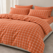 Calla Check Bedding Set in Burnt Tangerine, styled on a bed with checked quilt cover and pillowcases with button closures