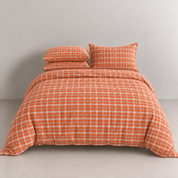 Calla Check Bedding Set in Burnt Tangerine, made bed showing tat check cotton and button closure detail