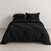 Camila Bedding Set in Black, rosette texture pulled into diamond shapes on a made bed with matching pillowcases