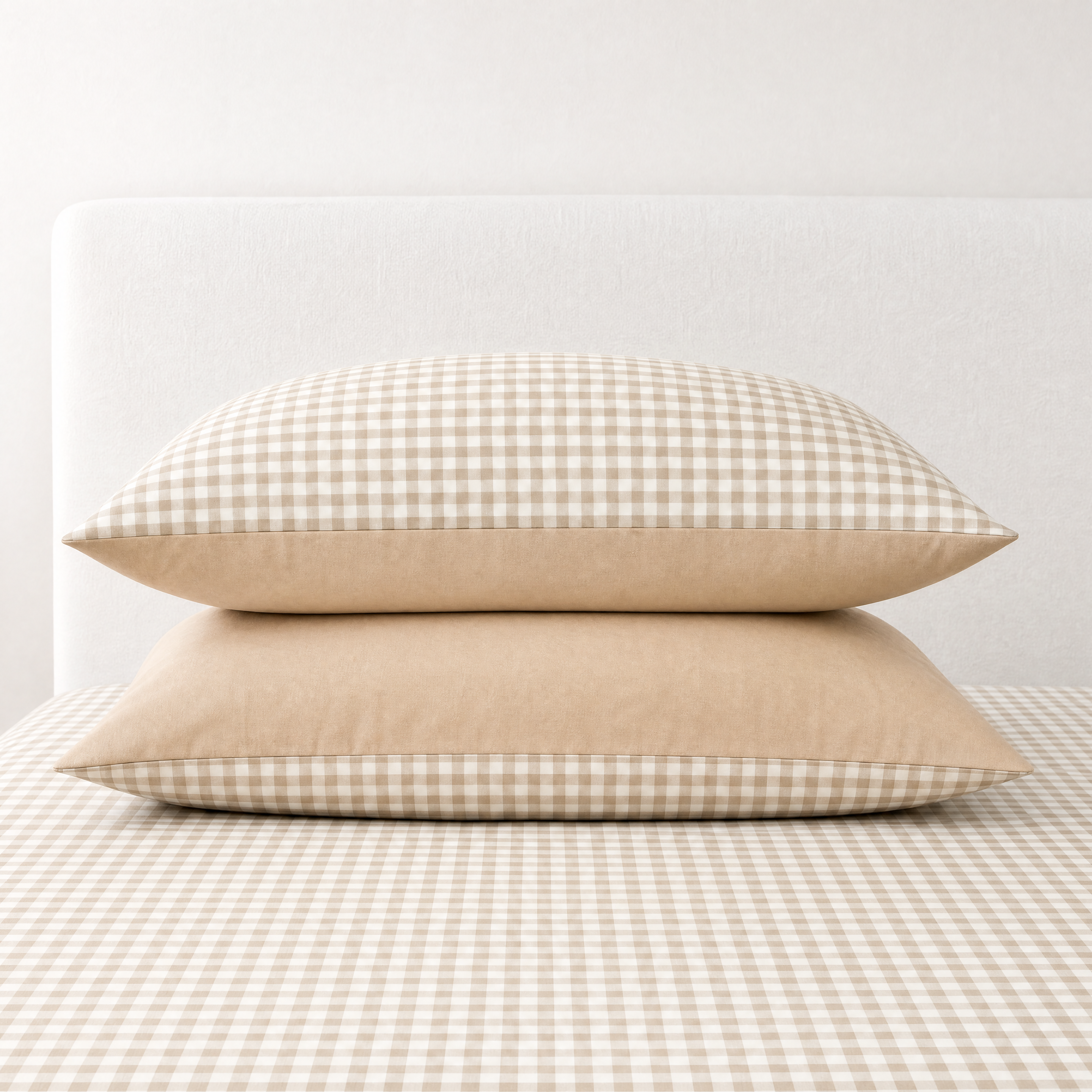 Two pillowcases from the Checkerboard Bedding Set in Coffee, tan gingham check with a solid reverse, stacked on the bed