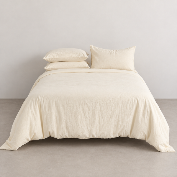 Coastal Washed Bedding Set in Oat Milk, crinkled quilt cover and pillowcases on a made bed against a plain wall