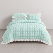 Esmé Ruffle Bedding Set in Aqua on a made bed, quilted grid texture with white ruffle trim