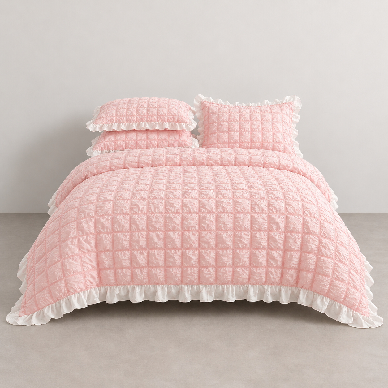 Esmé Ruffle Bedding Set in Blush, made bed with quilted squares and white ruffled edge trim