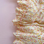 Close-up of ruffle trim on the Honeybelle Floral Ruffle Bedding Set, pink and yellow blooms on cream cotton