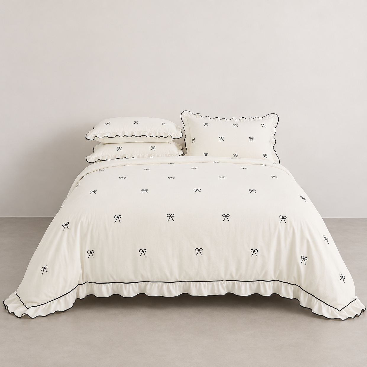 Isabella Bow Bedding Set in Ivory, made bed with bow embroidery and black-edged scalloped trim