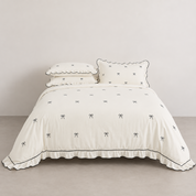 Isabella Bow Bedding Set in Ivory, made bed with bow embroidery and black-edged scalloped trim