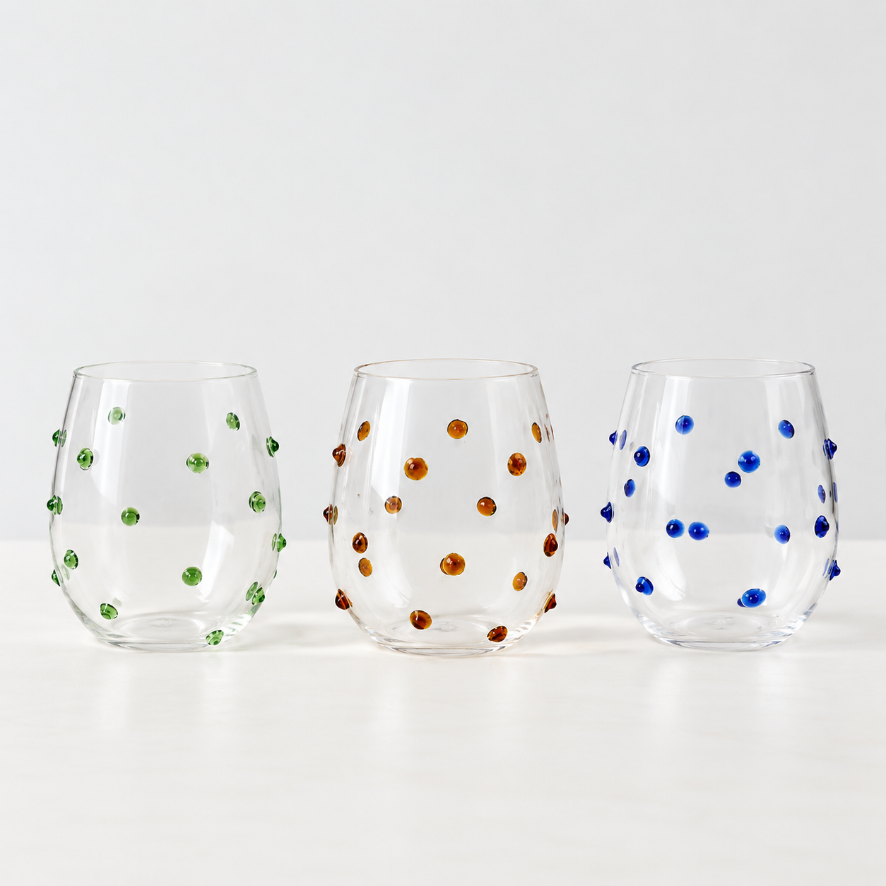 Isla Freckle Glass Tumbler in green, amber and blue, three stemless glasses shown side by side