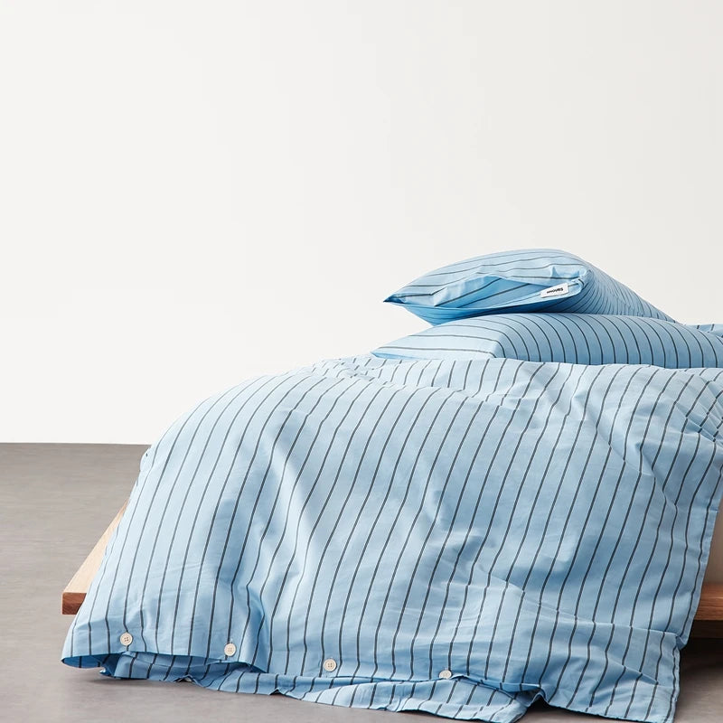 Juno Stripe Bedding Set in Baltic Blue, pinstripe cotton quilt cover with button closures on a made bed