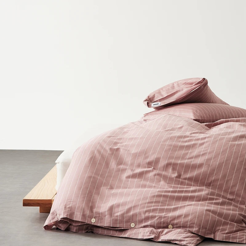Juno Stripe Bedding Set in Dusty Plum, rumpled quilt cover with pinstripe and button closure on a low bed