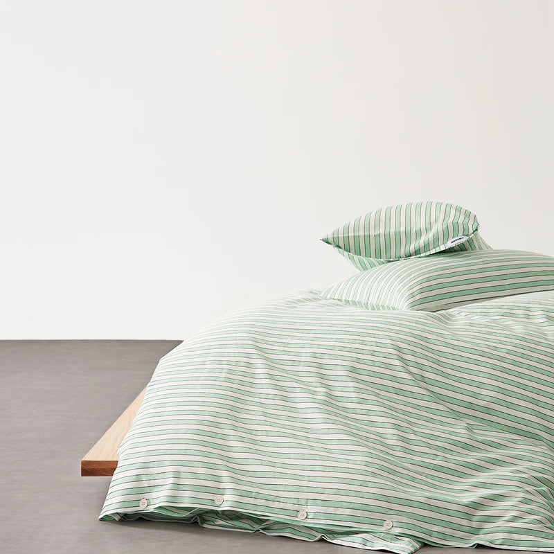 Juno Stripe Bedding Set in Sage, green and white stripes on a low bed with timber frame, button closure shown