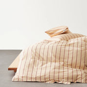 Juno Stripe Bedding Set in Sandstone, rust stripes on cotton with button-closure quilt cover on a low bed frame