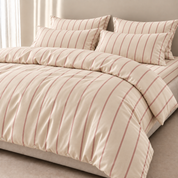Juno Stripe Bedding Set in cream cotton with dusty pink stripes, styled on a made bed with pillows