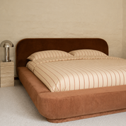 Juno Stripe Bedding Set in cream with rust pinstripes, styled on a bed with a velvet headboard