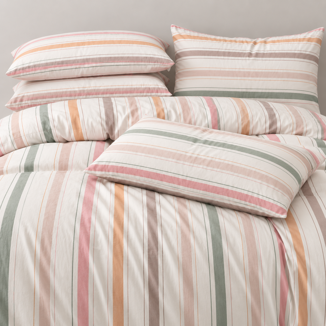 Layla Striped Bedding Set pillows and quilt cover stacked, showing pink, green and orange stripes on cotton