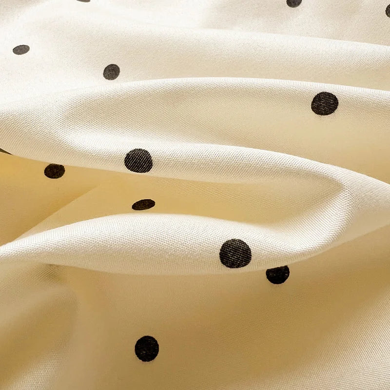 Close-up of the Lenny Spot Bedding Set, black spots scattered over softly draped cream cotton blend fabric
