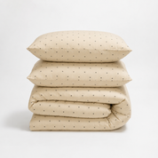 Lenny Spot Bedding Set folded in a stack, cream fabric with fine grey spot pattern, on white