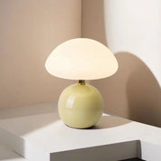Lumi Mushroom Table Lamp with glossy pale green ball base and domed white glass shade, lit on a plinth