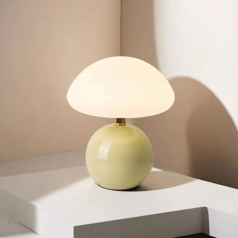 Lumi Mushroom Table Lamp with glossy pale green ball base and domed white glass shade, lit on a plinth