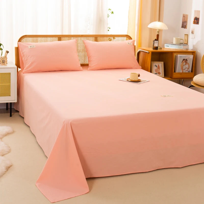 Luna Cotton Flat Sheet in Apricot Sorbet, styled on a rattan bed with matching pillowcases