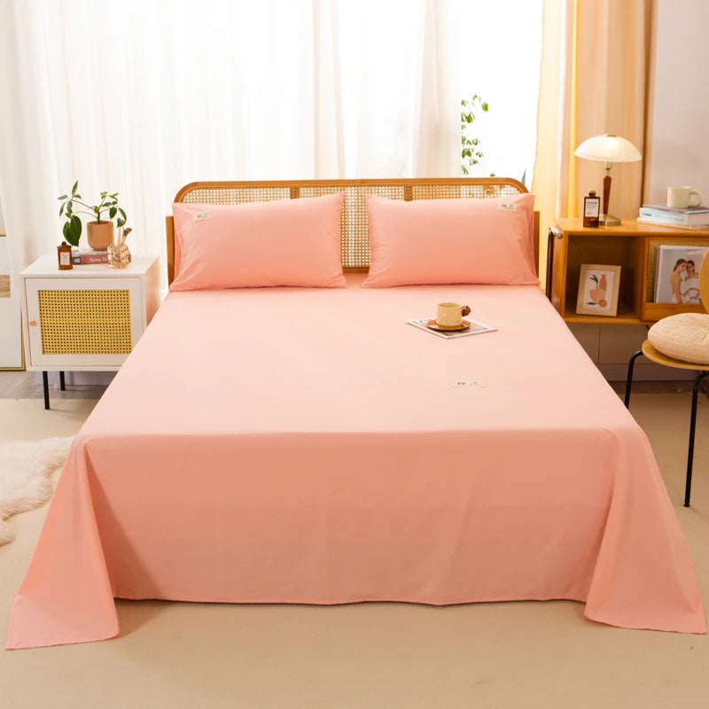 Luna Cotton Flat Sheet in Apricot Sorbet dressed on a rattan bed with matching pillowcases