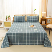 Luna Cotton Flat Sheet in Coastal Check, slate blue grid on a rattan bed with matching pillowcases