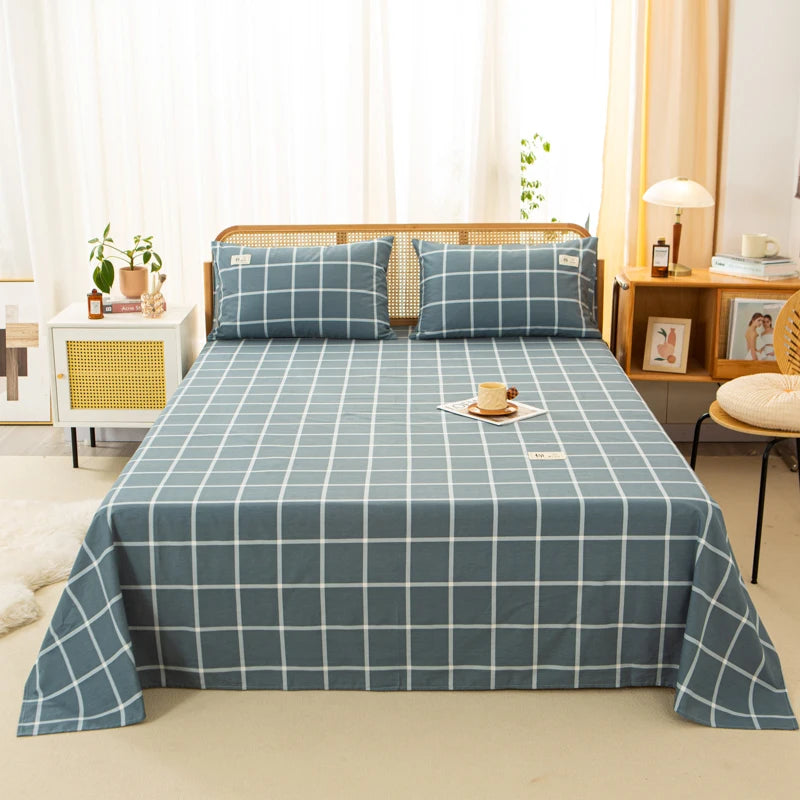 Luna Cotton Flat Sheet in Coastal Check, slate blue grid on a rattan bed with matching pillowcases
