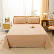 Luna Cotton Flat Sheet in Oat Milk dressing a bed with cane headboard and matching pillowcases
