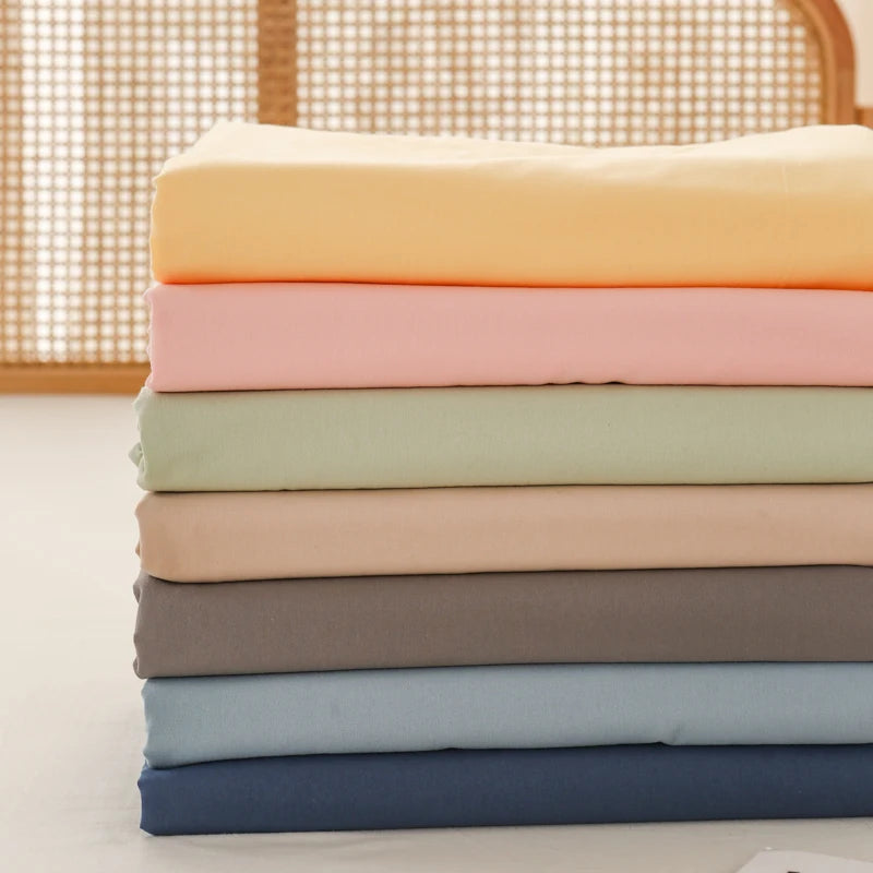 Luna Cotton Flat Sheet folded stack in yellow, apricot, sage, oat, grey, blue and navy tones