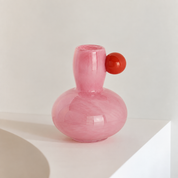 Marley Pastel Vase in Pink, gourd shaped glass body with a red sphere accent at the neck, on a white ledge