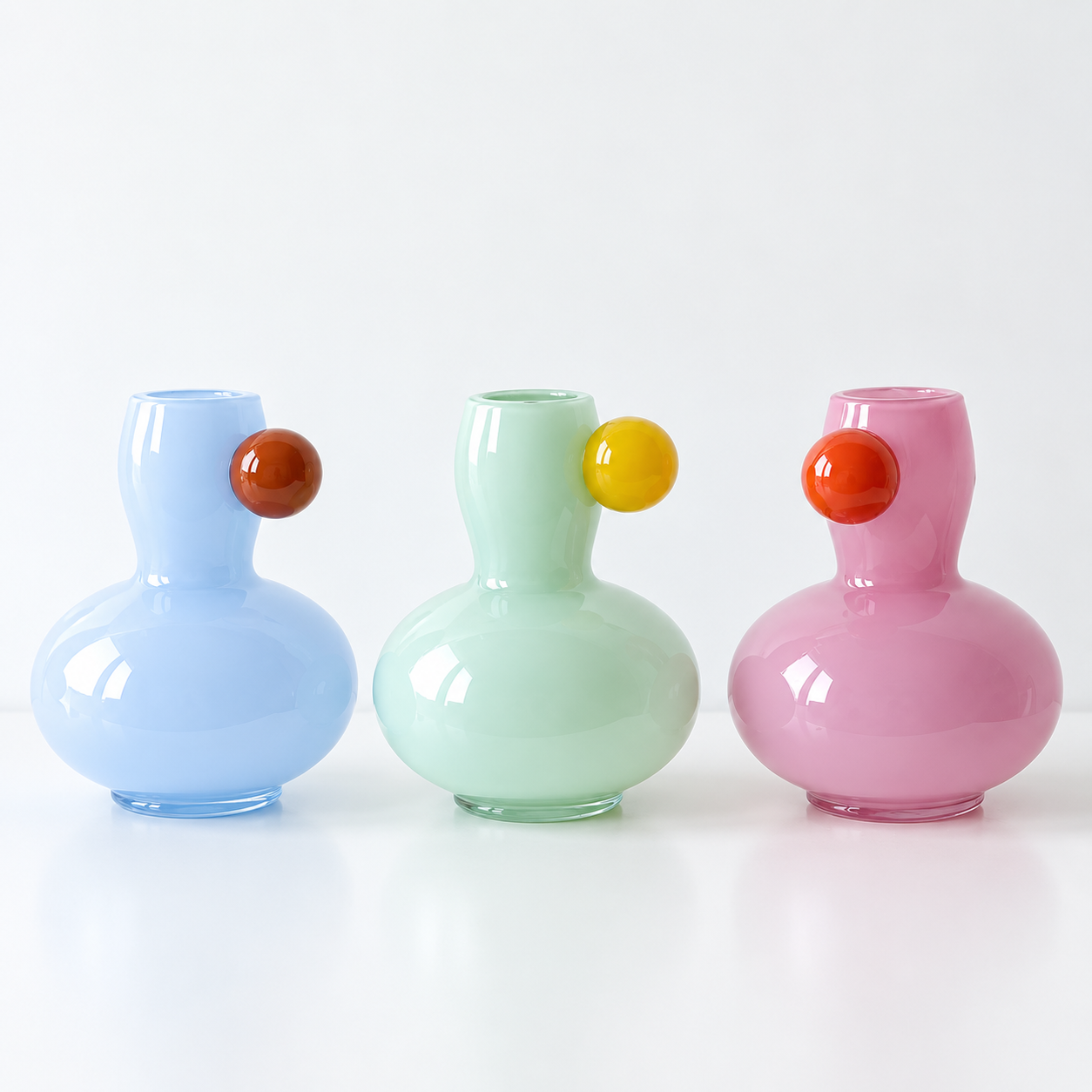Marley Pastel Vase shown in blue, green and pink glass, each with a contrasting sphere at the neck