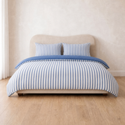 Marseille Stripe Bedding Set in Blueberry Cream, blue and white stripes on a made bed with wooden floor