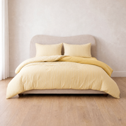 Marseille Stripe Bedding Set in Lemon Butter, striped quilt cover on a made bed with folded-back corner