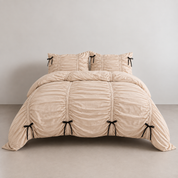 Metaya Bedding Set in Beige, ruched quilt cover and pillowcases on a bed with black tie details