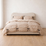 Metaya Bedding Set in Beige, ruched cotton twill with black ties, styled on a made bed