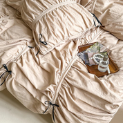 Metaya Bedding Set in Beige, rumpled cotton twill with tie corners, styled tray of trinkets nearby