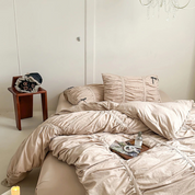 Metaya Bedding Set in Beige, rumpled quilt cover and pillowcases styled on a bed with a tray of trinkets