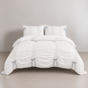 Metaya Bedding Set in Blue & White, ruched quilt cover with pale blue ribbon ties on a made bed