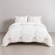 Metaya Bedding Set in Pink & White, ruched white cotton with pink ribbon ties on a made bed