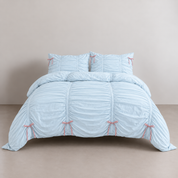 Metaya Bedding Set in Sky Blue, ruched quilt cover and pillowcases with pink tie details on a made bed