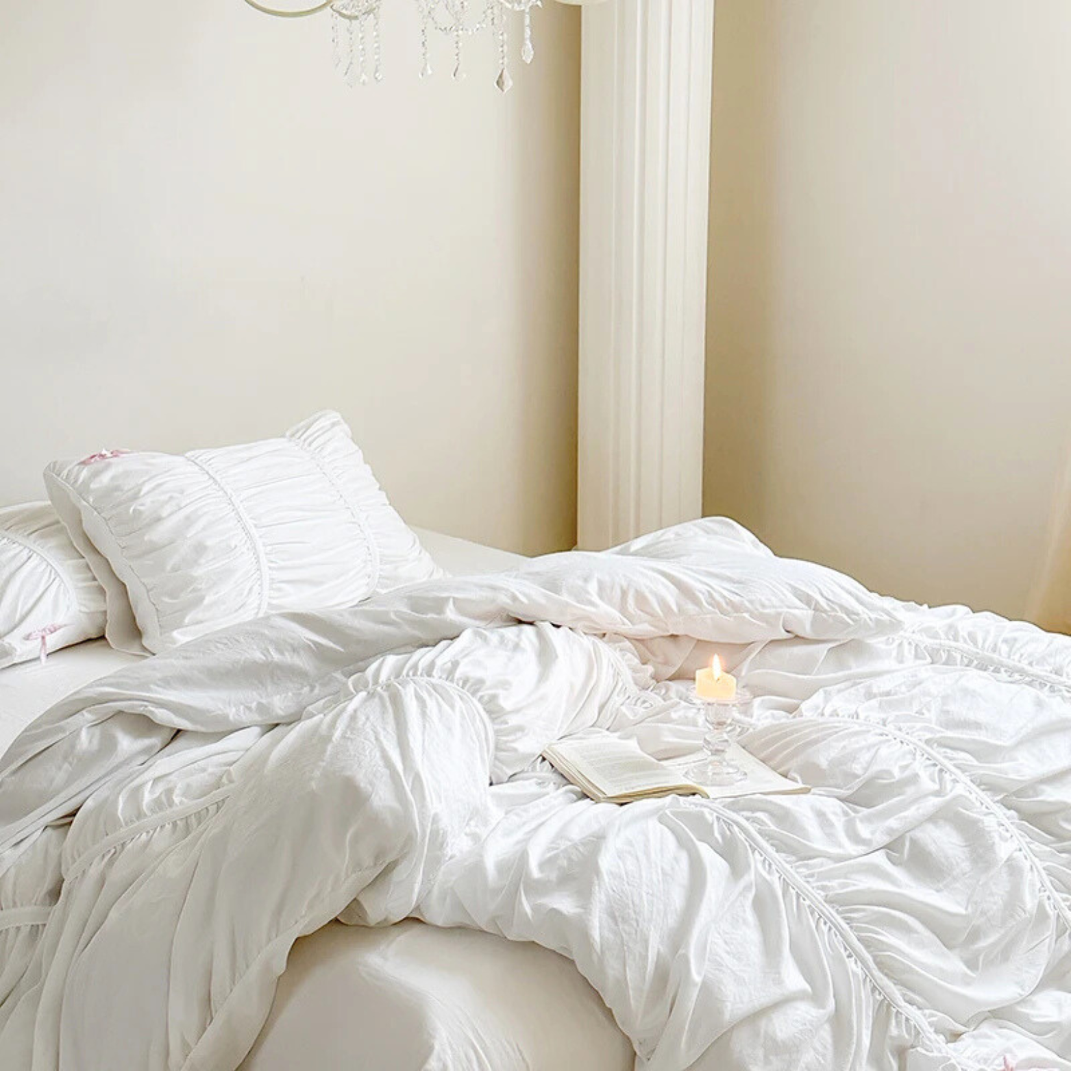 Metaya Bedding Set in soft white, ruched quilt cover rumpled on a bed with candle and open book