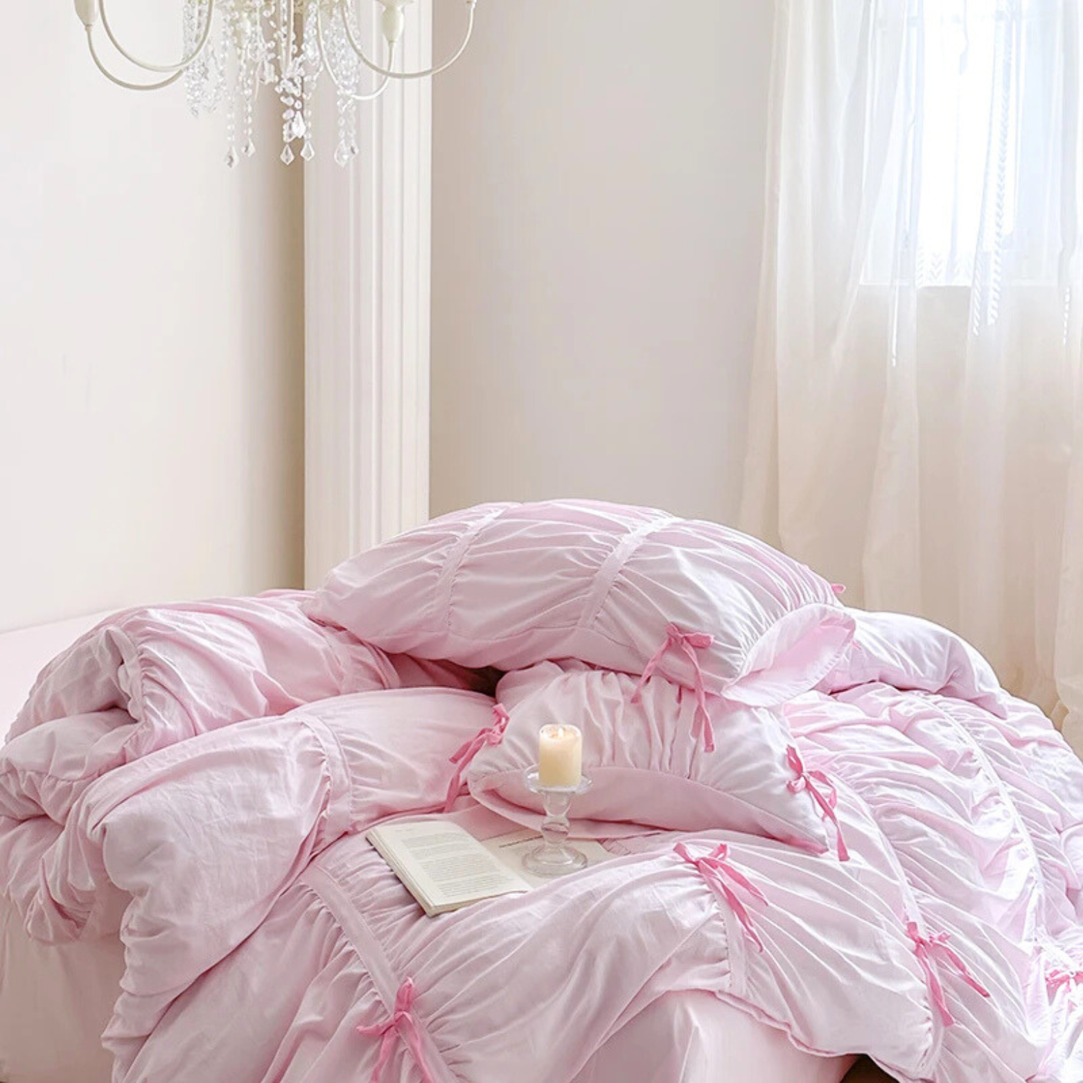 Metaya Bedding Set in soft pink with ruched texture and ribbon ties, styled bed by a window with candle and book