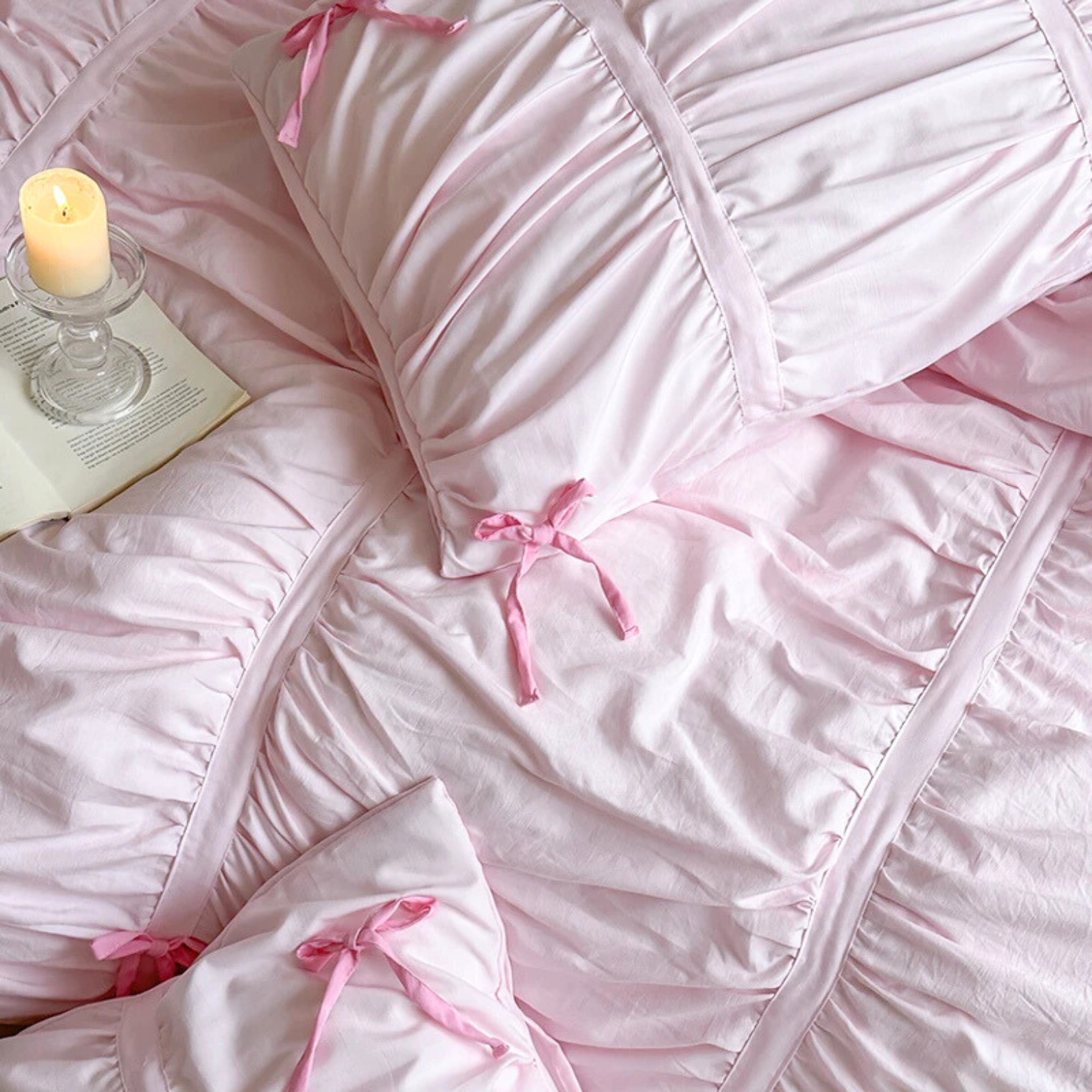 Metaya Bedding Set in blush pink with ruched texture and ribbon ties, styled with a candle and open book