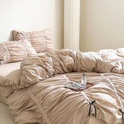 Metaya Bedding Set in beige twill cotton, ruched with tie details, styled on a bed with a small tray