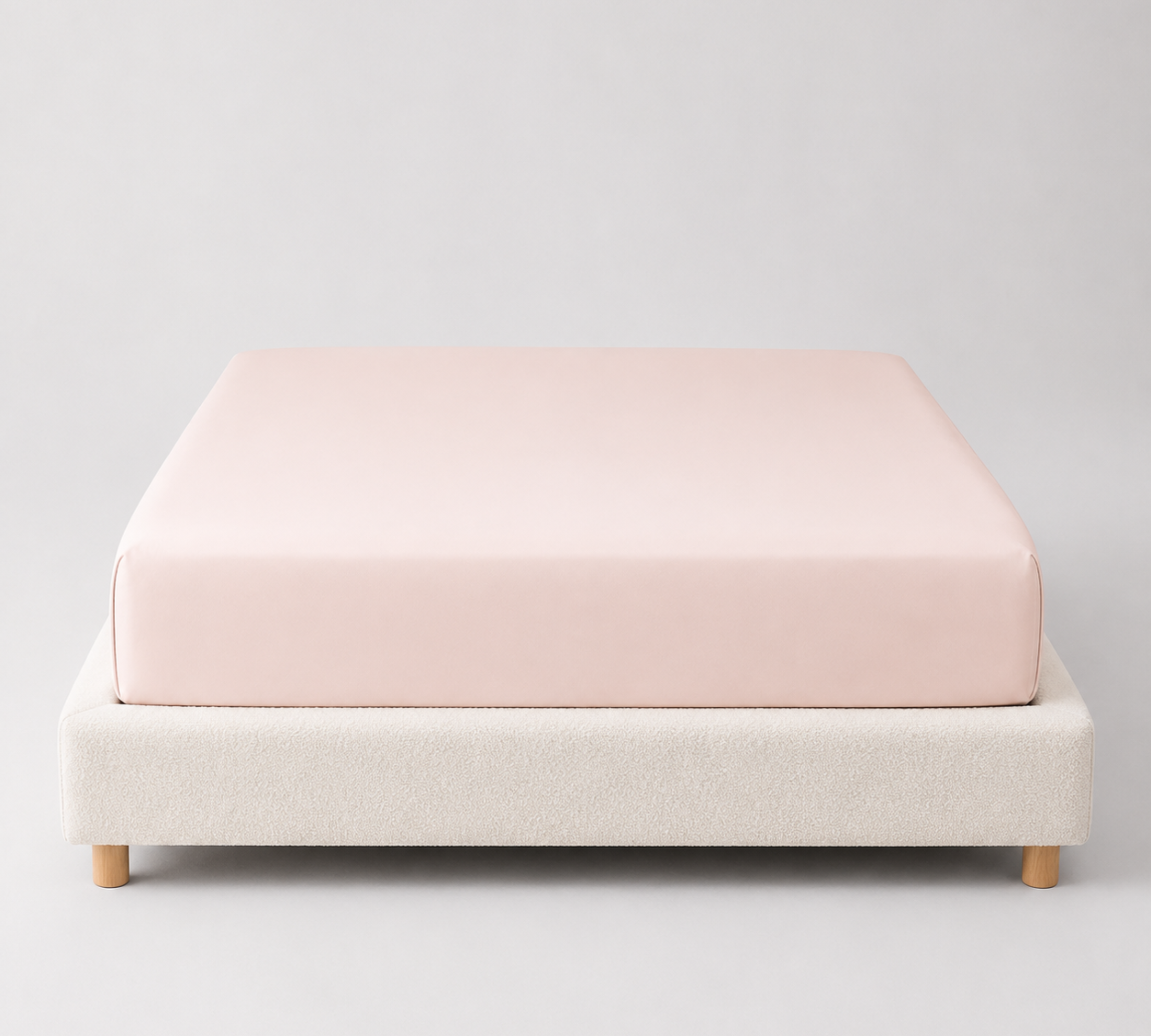 Mira Bamboo Fitted Sheet in Blush, soft pink smooth fabric fitted over a bare mattress base