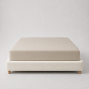 Mira Bamboo Fitted Sheet in Champagne, smooth stretched over a mattress on a wooden-leg base