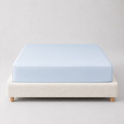 Mira Bamboo Fitted Sheet in Sky, pale blue, fitted smoothly over a mattress on a bouclé bed base