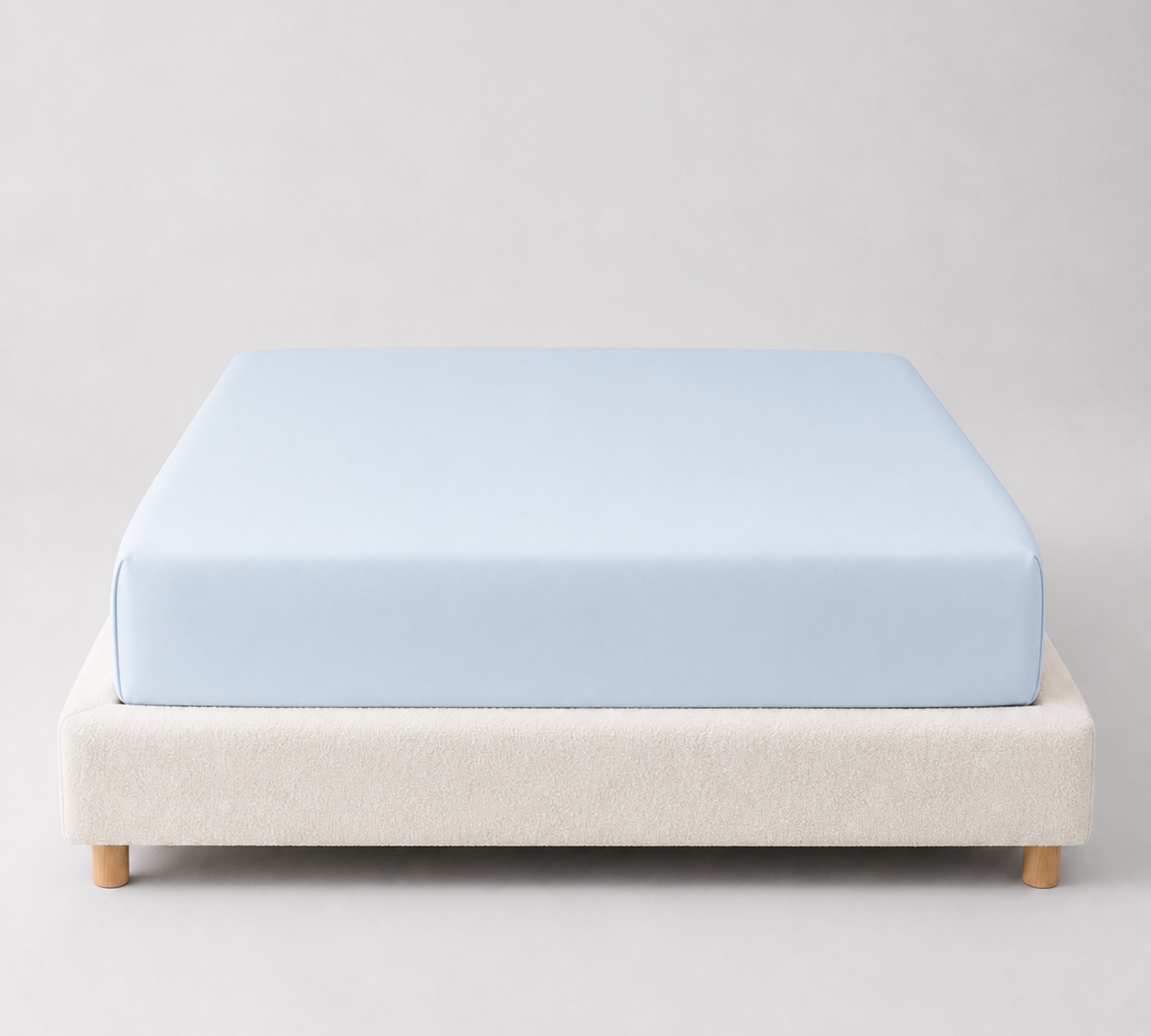 Mira Bamboo Fitted Sheet in Sky, pale blue, fitted smoothly over a mattress on a bouclé bed base