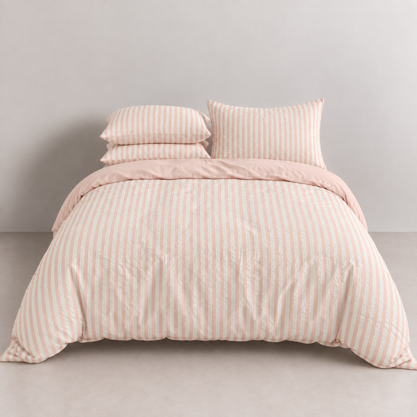 Noah Bedding Set in Blush, soft pink stripe quilt cover styled on a made bed with matching pillowcases