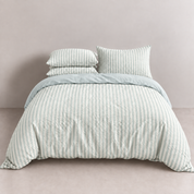 Noah Bedding Set in Sky, pale blue striped quilt cover on a made bed with matching pillowcases stacked